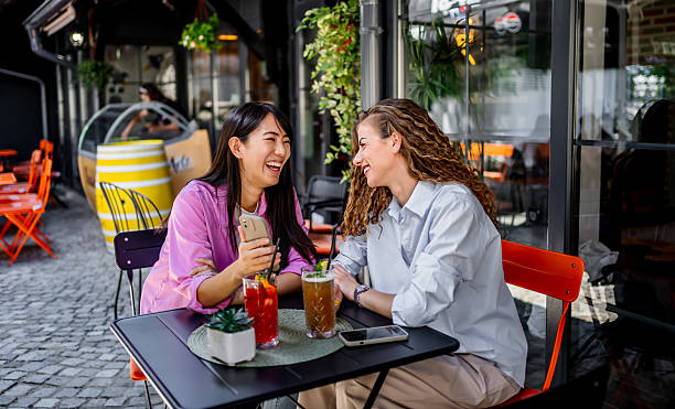 istock Diverse friends laughing at outdoor cafe using smartphone 2239534079