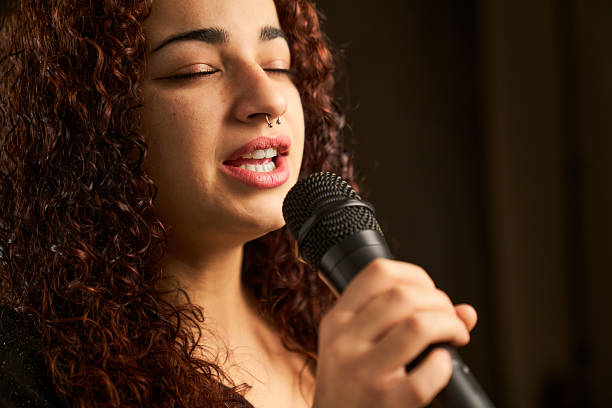 istock Woman with curly hair singing into microphone 2239535030