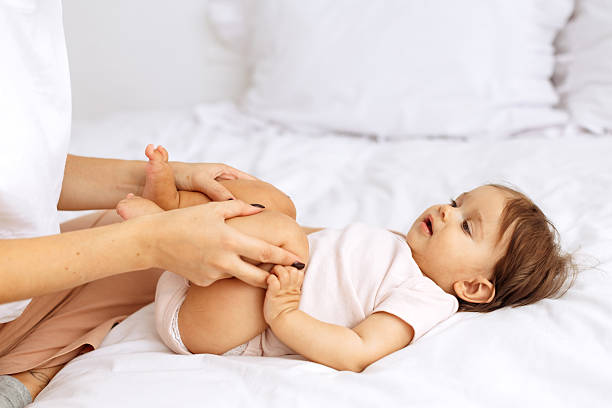 istock Cute little baby lying on bed while mother gently playing with legs 2239537202