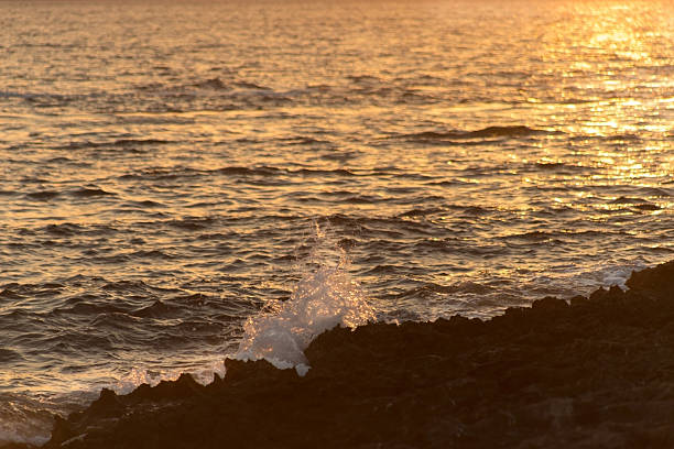 Beautiful seascape with rocky coastline illuminated by warm sunset light. Golden tones, calm waves, and glowing sky create a peaceful and romantic atmosphere. Perfect for travel, nature, and landscape concepts. High quality photo