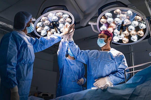 chirurgen feiern im operationssaal - nurse high five mask stock-fotos und bilder
