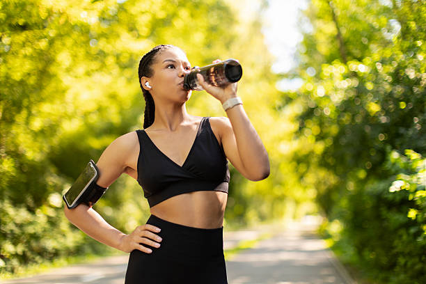 istock African American woman drinking water from bottle outdoors after jogging, showing hydration 2239549749