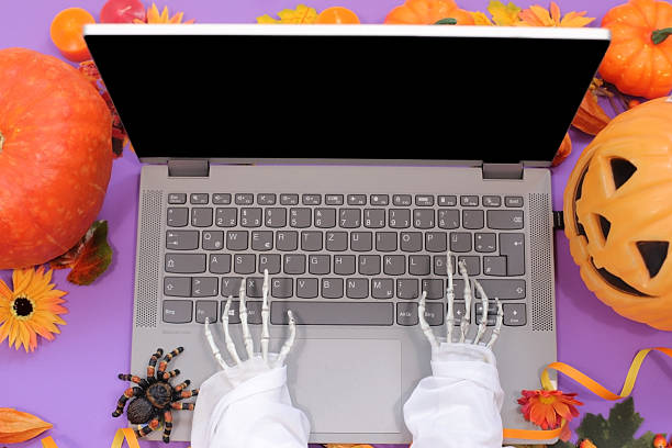 istock Deadlines & Dead Things: Skeleton at Laptop with Fall and Hallowen Decor on purple background 2239550774