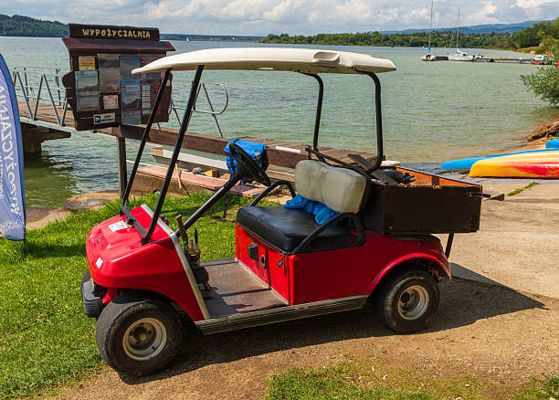 A group of golfers ride in a golf cart on a picturesque golf course, surrounded by the vibrant colors of autumn. Majestic trees with golden leaves create a serene and peaceful atmosphere. This image captures a moment of leisure and enjoyment in the great outdoors, perfect for golf enthusiasts.