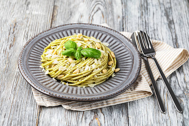 Pasta spaghetti with pesto sauce and fresh basil leaves. Isolated on white background.