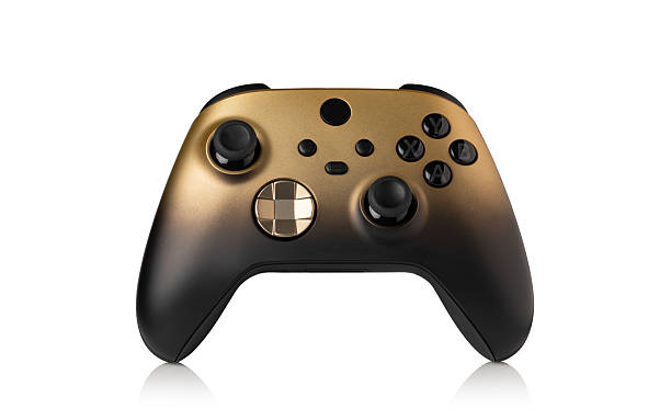 istock Black and gold video game controller resting on white background 2239554751