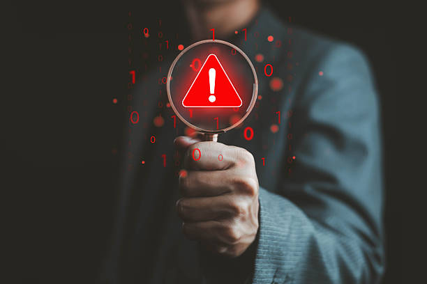 istock Businessman holding magnifying glass with red warning alert symbol, representing cybersecurity risk detection data breach analysis internet security threat, and system error alert concept for digital. 2239555213