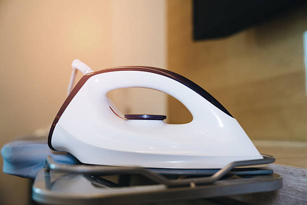 Modern steam iron resting on an ironing board in a bright room with warm lighting for efficient laundry organization and styling.