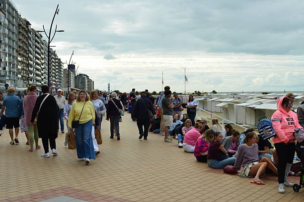 Blankenberge, West-Flanders, Belgium - August 30, 2025: Sitting teenagers on the ground. People wait in long lines on promenade well in advance for the free annual music event evening show at the end of summer