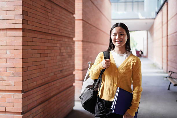 istock Portrait of smiling high school student with backpack and planner standing on school campus 2239566395