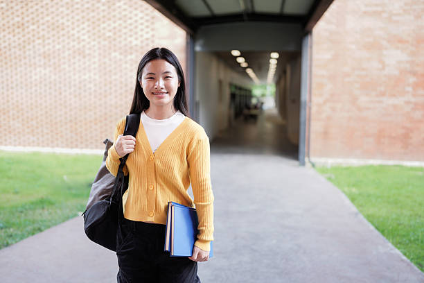 istock Portrait of smiling high school student with backpack and planner standing on school campus 2239566417
