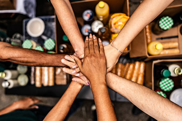 Close-up of people stacking hands over donation boxes