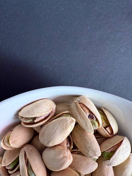 Pistachios in a white bowl. Bowl of pistachios on dark background.