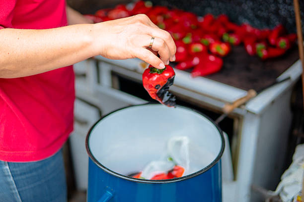 Woman roasting red bell peppers. Close up of hands and papers.