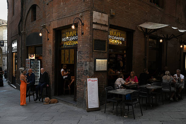 Siena, Italy, september 15, 2025 : Bar-restaurant-pizzeria on the corner of a rue de Sienne with customers seated on the terrace