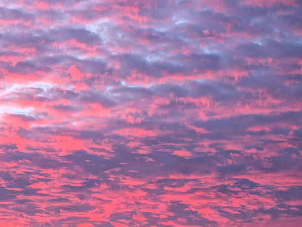 The sky is filled with vibrant pinks and purples during sunset, creating a peaceful and serene atmosphere. Soft clouds add texture to the breathtaking view.