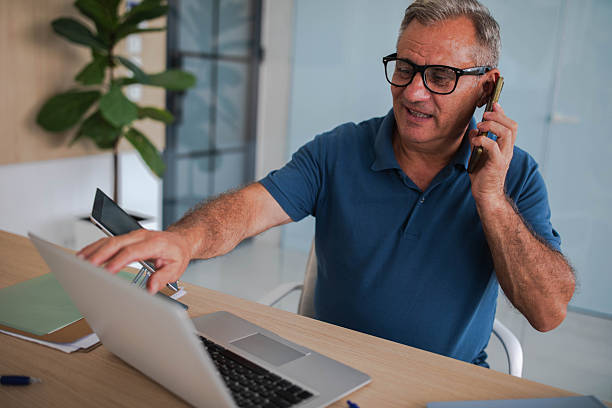 istock Senior businessman working in office, using laptop and smartphone 2239576332