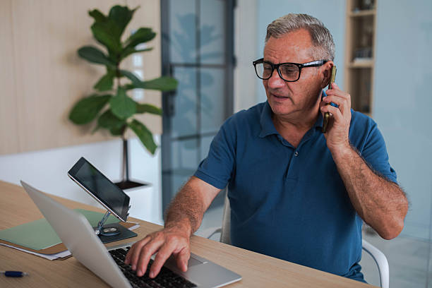 istock Senior businessman working in office, using laptop and smartphone 2239576368
