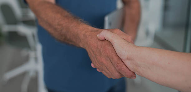 istock An older businessman with his hand outstretched shakes hands with another unrecognizable person 2239576397