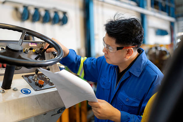 istock Airport engineer wearing uniform and safety glasses tests new lubricant for cargo loader truck. Records equipment usage time from cargo loader dashboard. 2239576553