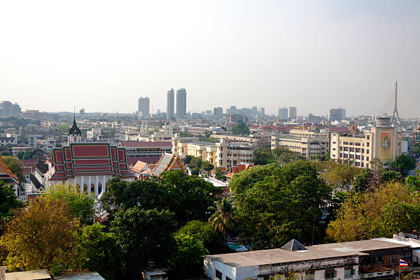View over old Bangkok to the West and  river Chao Phraya at afternoon. In area is Royal Rattanakosin Hotel. In left area is Wat Ratchanatdaram Worawihan. In right background is Rama VII bridge.  View from  temple Golden Mountain Saket. Wat Saket is one of oldest temples in Bangkok and placed on a hill and is located in district Pom Prap Sattru Phai. Wat Saket offers 360 degree lookout of inner Bangkok