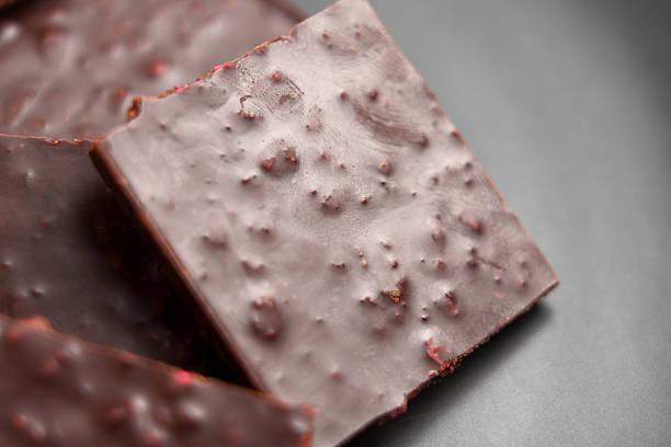 Squares of broken dark chocolate bar with strawberry filling on a black ceramic platter.
