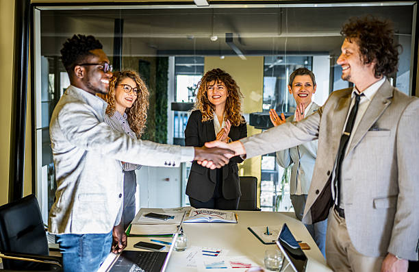 istock Diverse business partners shaking hands after successful meeting. Adults only, analyzing, black people, board room, brainstorming, business, business meeting, busine 2239591127