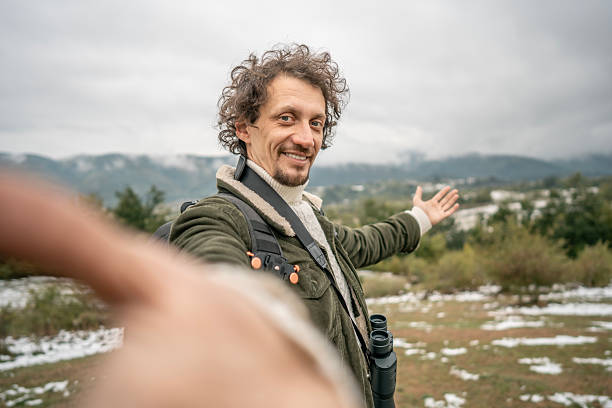 istock Adventurous Man With Backpack In Snowy Field Extends Arms Toward Scenic Mountain Landscape 2239591283