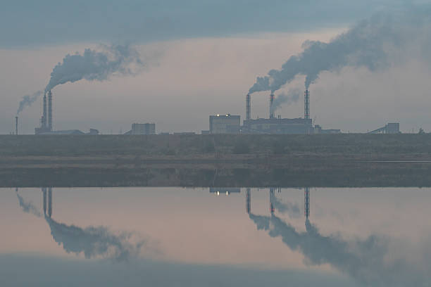 istock a factory on the river bank. Smoking chimneys 2239592398