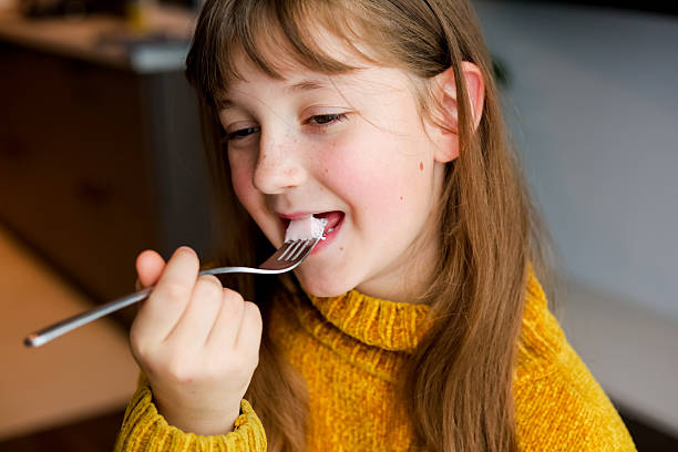 istock Child eating pudding with a fork in a yellow sweater 2239592868