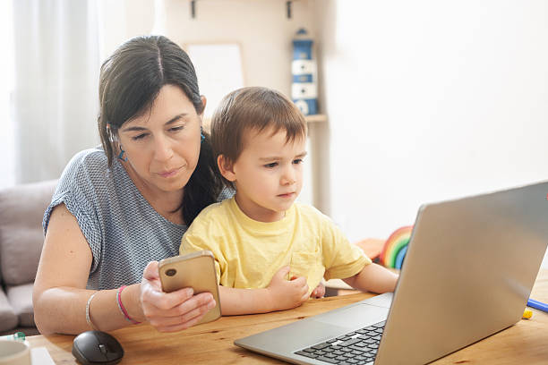 istock Mother holding phone while working with toddler on her lap 2239595945