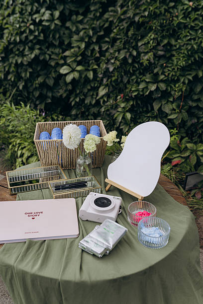 Stylish Wedding Preparation Table with Album, Instant Camera, and Elegant Decor Items Surrounded by Greenery for a Lovely and Romantic Ambiance