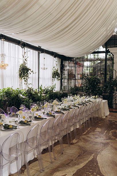 istock Elegant Dining Setup in a Lush Greenery Space with Beautiful Table Arrangement Featuring Clear Chairs and Tasteful Decor for Special Occasions Like Weddings or Events 2239600361