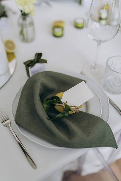 Elegant Table Setting Showcasing Stylish Table Decor with Green Napkin, Lemon, and Charming Favors Perfect for Special Events, Weddings, or Celebrations with Sophisticated Ambiance