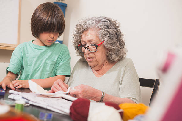 istock Grandmother sewing while grandson watches attentively 2239603336
