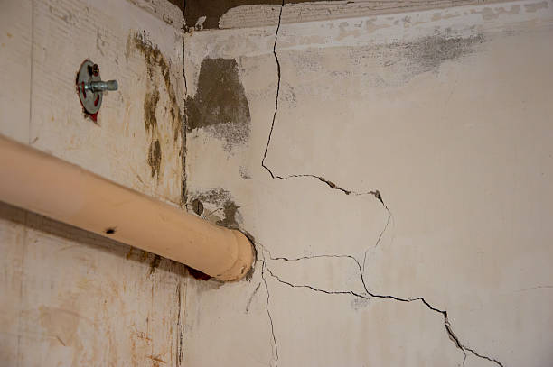 istock Visible cracks along the wall and ceiling near a plumbing pipe suggest potential problems in the structure of the building 2239605202
