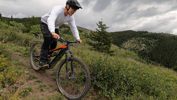istock Male mountain biker descends steep trail from mountain top 2239607476