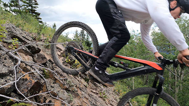 istock Male mountain biker descends steep trail from mountain top 2239607497