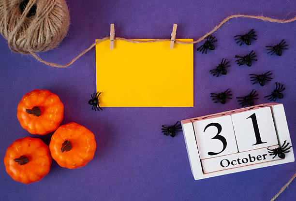 Halloween composition with pumpkins, spiders and October 31 calendar on purple background. Perfect seasonal design.