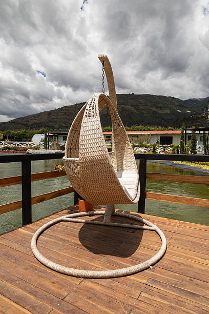 Wicker hammock chair hanging outdoors on a wooden base in a serene garden setting