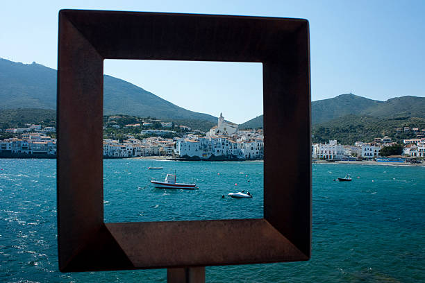 Rustic metal frame highlighting the picturesque Cadaques village and its bay with boats, offering a unique perspective of this popular tourist destination on the Costa Brava