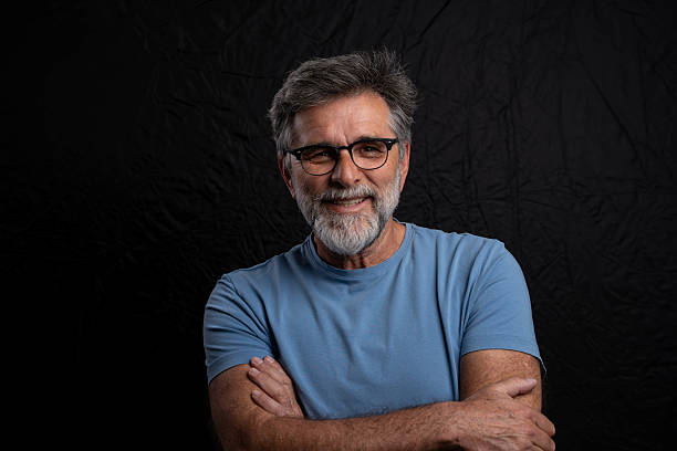 istock Smiling businessman with arms crossed, confident pose under chiaroscuro lighting, studio shot on dark background 2239617011