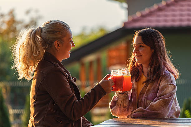 Mother and daughter drinking smoothie while sitting in the backyard