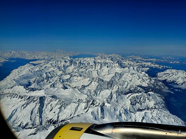 Several mountain peaks in the Swiss Alps. The image was captured on a commercial flight during spring season.