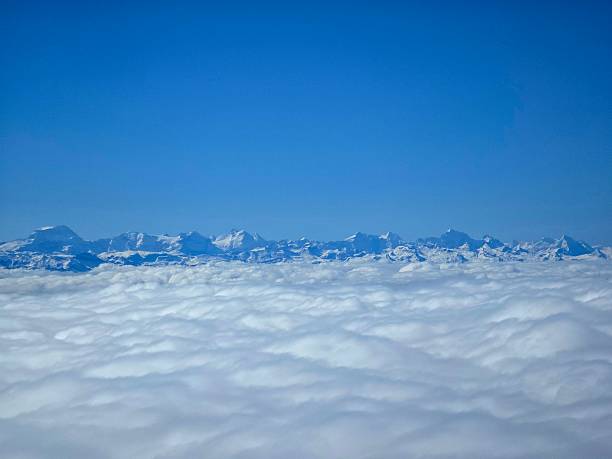 Several mountain peaks in the Swiss Alps. The image was captured on a commercial flight. Captured during spring season.