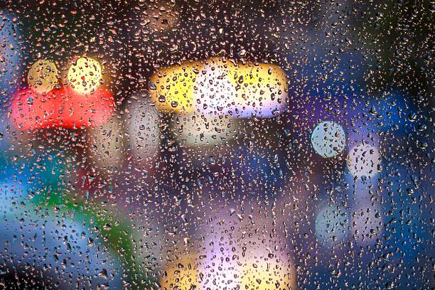istock Rain drops on window with colorful city lights at night with bokeh. 2239621101