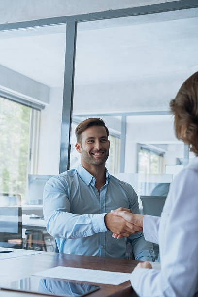 istock Young Latin bank worker man shaking hand with client, recruit employee on interview or business partner after signing contract. Group of people satisfied with results of team work together. Vertical 2239626782