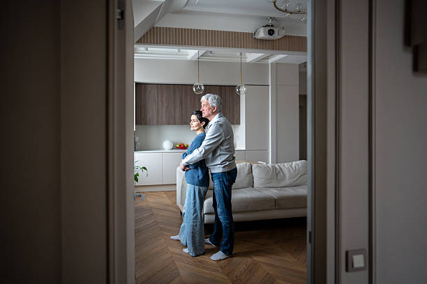 istock Elderly loving couple hugging looking out window. Mature romance support, aging together with trust 2239629568