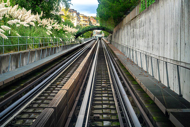 Railway tracks of Lausanne underground leading into a tunnel surrounded by greenery.
