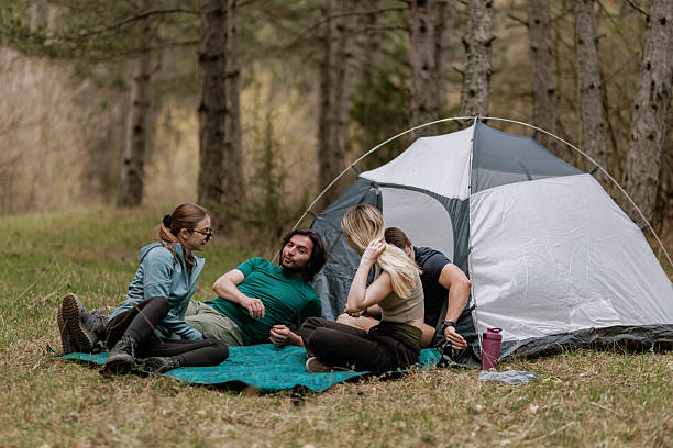 istock Friends enjoy a relaxing camping experience in a forest clearing on a sunny afternoon while sitting on a blanket near their tent 2239648392